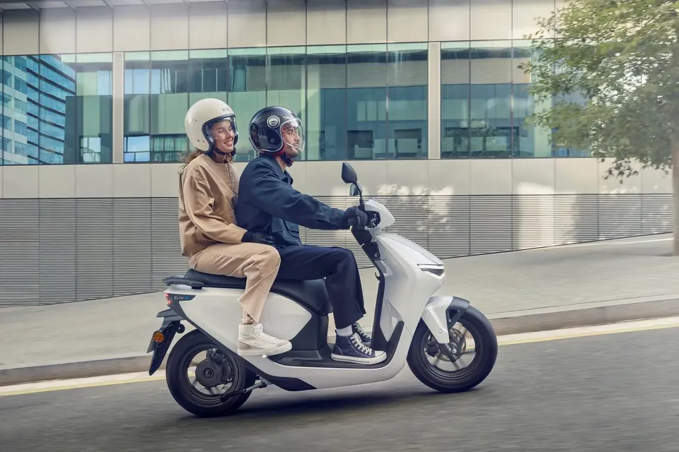 Electric scooter Honda CUV e: with two people in front of an office building