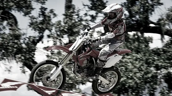 Teenager jumping over a crest on the youth motocross Honda CRF150R