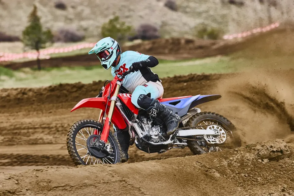 Pilote couchant la CRF250R dans un virage, la terre gicle