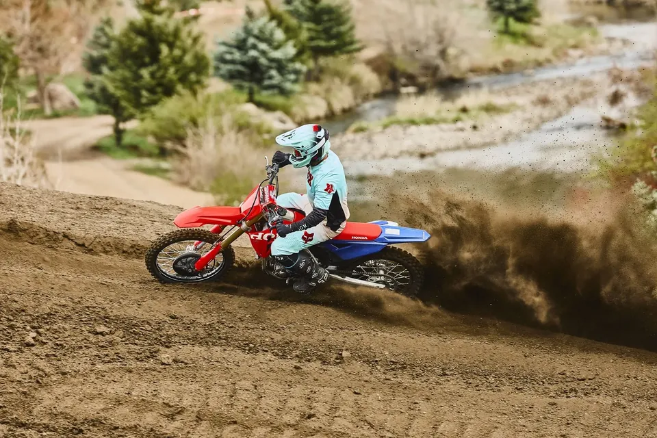 Moto de cross 250 Honda CRF250R sur la piste, devant des arbres